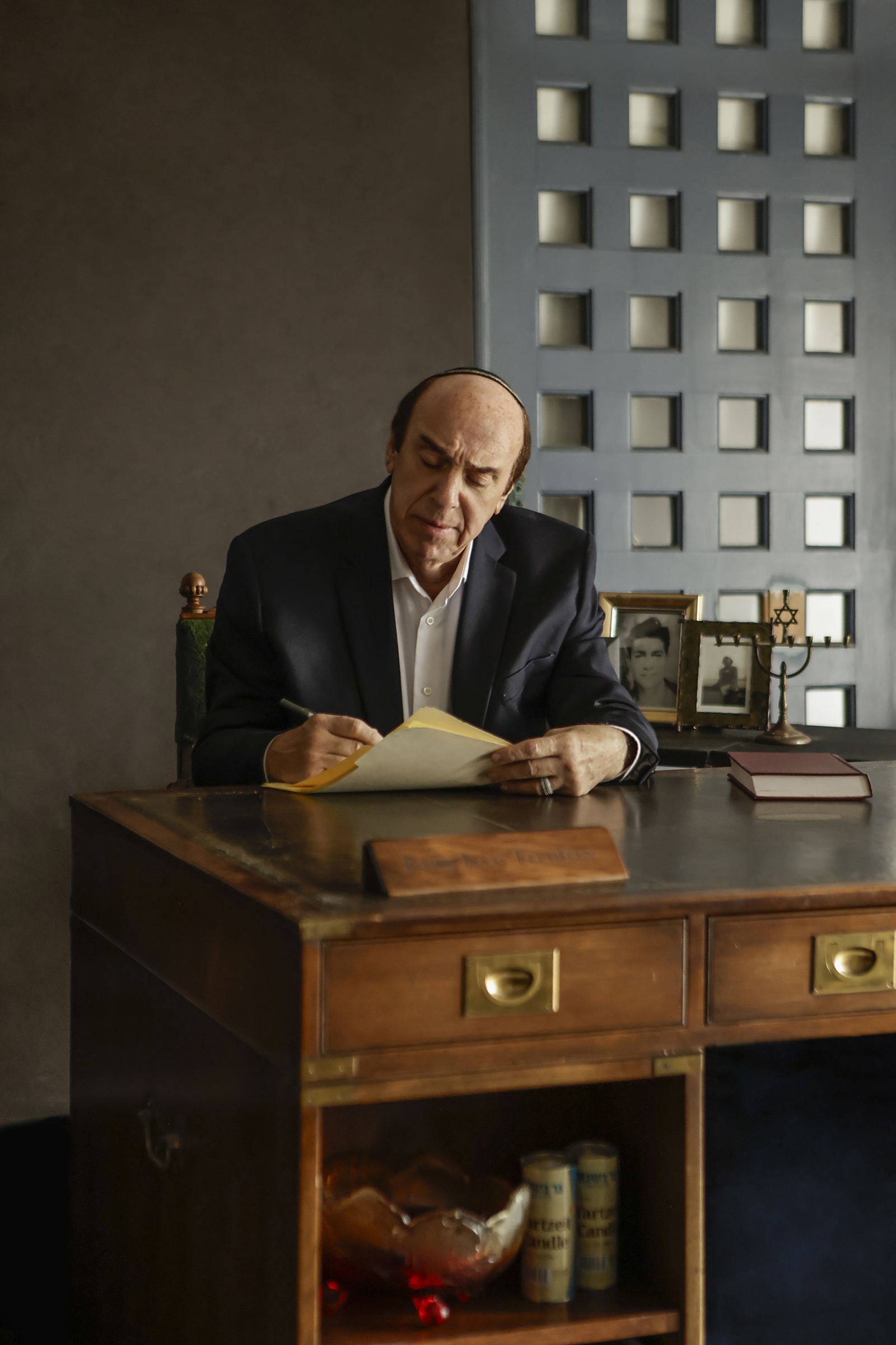 09-29-26_SorchaAugustine_091556-FINAL Actor seated at a desk writing on documents during a scene from Kaddish for the Barrio.
