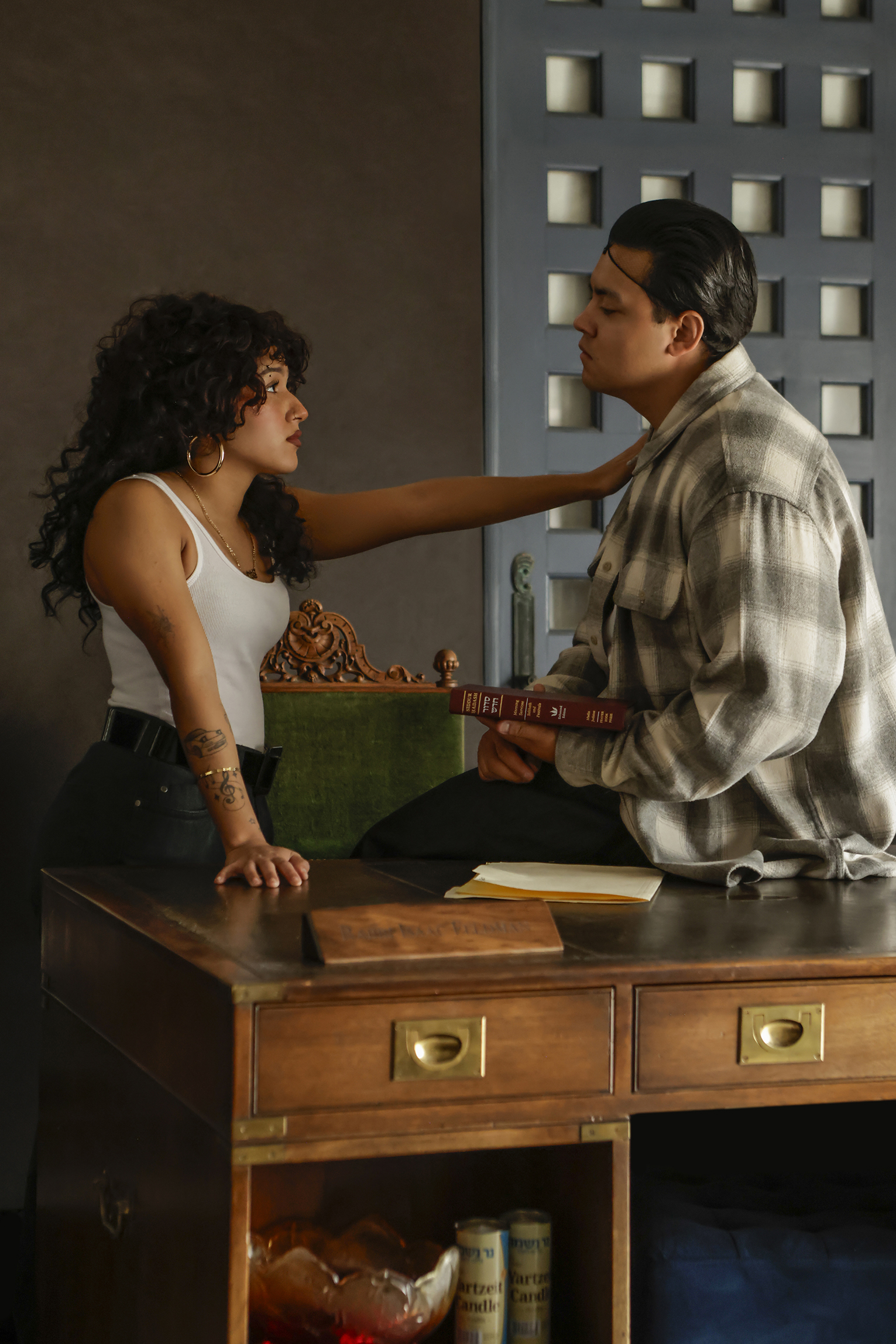 09-29-26_SorchaAugustine_093715-FINAL Two young actors face one another beside a desk, with one reaching toward the other, in Kaddish for the Barrio.